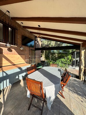 An outdoor dining area with a table and chairs, a brick wall, and a view of greenery. - Private chalet with pool, barbecue and fireplace, 1 hour from Madrid (Maello)