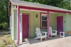 A small, single-story building with a green exterior and pink accents, featuring two white Adirondack chairs and a small table outside. - Soft Launch Deal: Sage Sojourn Studio (Saugerties)