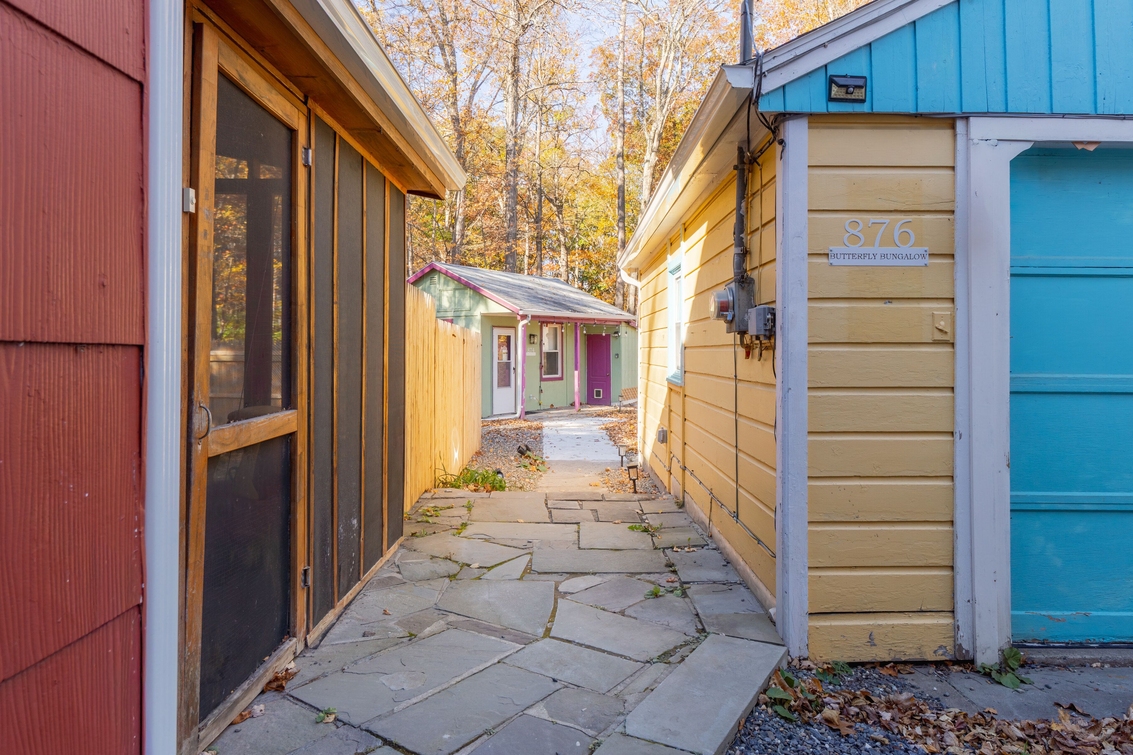 Un étroit sentier mène à une rangée de maisons mobiles aux couleurs vives, chacune étant identifiable par un numéro et une plaque nominative distincts.