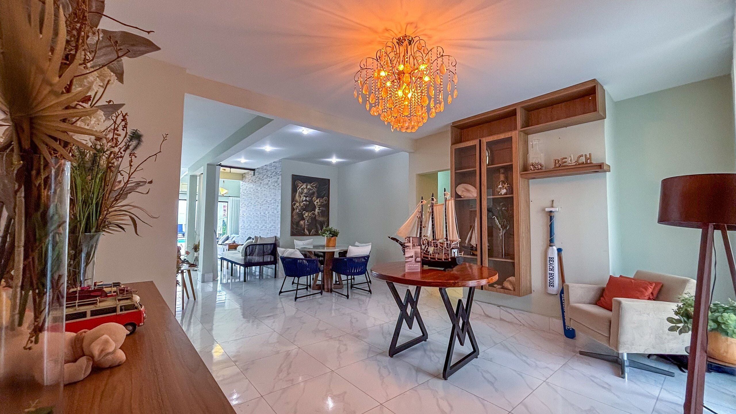Uma sala ampla com um lustre, uma mesa de jantar e um sofá.