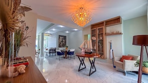 A spacious living area with a chandelier, a dining table, and a sofa. - SHB Condomínio com 5 Quartos e Lazer (Guarujá)