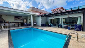 Uma piscina com área de estar, cozinha e sala de estar com televisão.