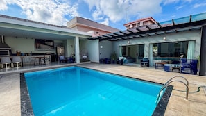A swimming pool with a patio area, a kitchen, and a living room with a TV. - SHB Condomínio com 5 Quartos e Lazer (Guarujá)