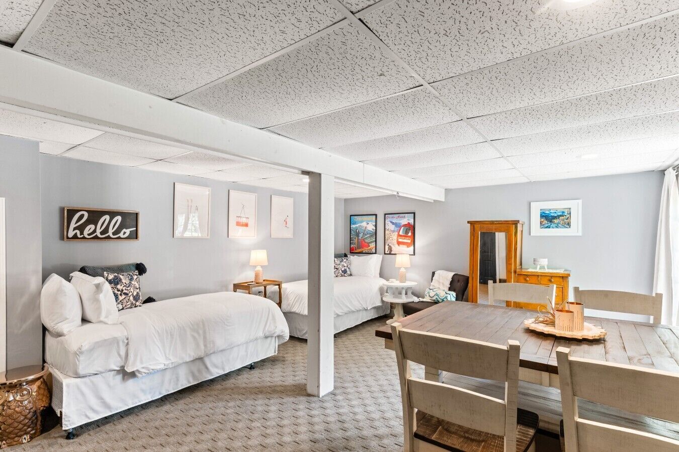 A room with two beds, a dining table, and a wooden cabinet.