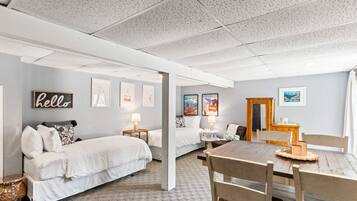 A room with two beds, a dining table, and a wooden cabinet.