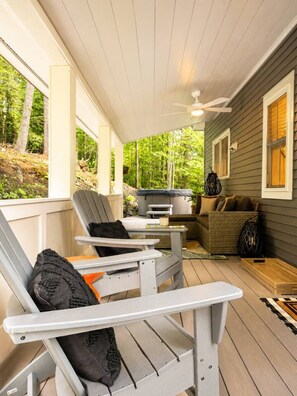 Une véranda abritée avec des fauteuils Adirondack, une table et un canapé.
