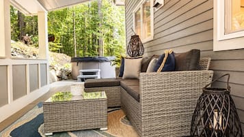 Une véranda aménagée avec des meubles en osier, une table basse en verre et une lanterne.