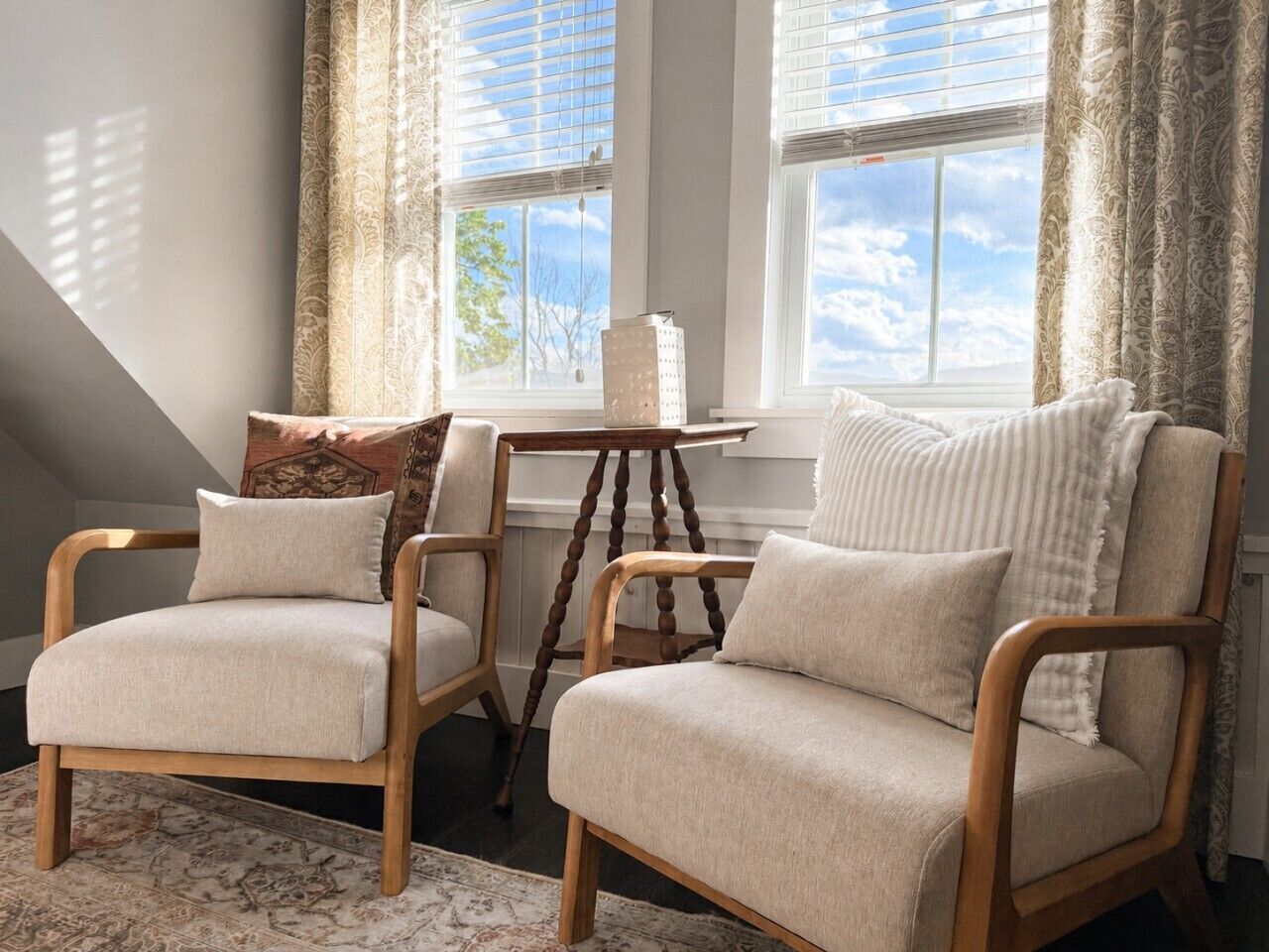 A room with two armchairs, a small table, and a window with curtains.