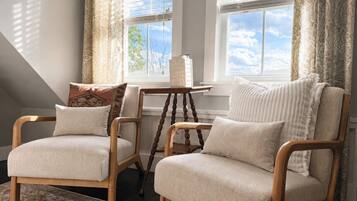 A room with two armchairs, a small table, and a window with curtains.