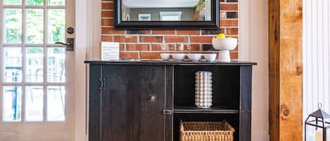 A dark wooden cabinet with a mirror above it, a wicker basket, and a white vase on the top shelf.