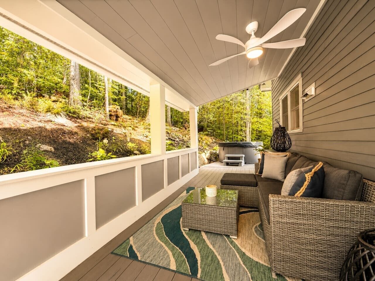 A covered outdoor area with a sofa, a table, and a ceiling fan.