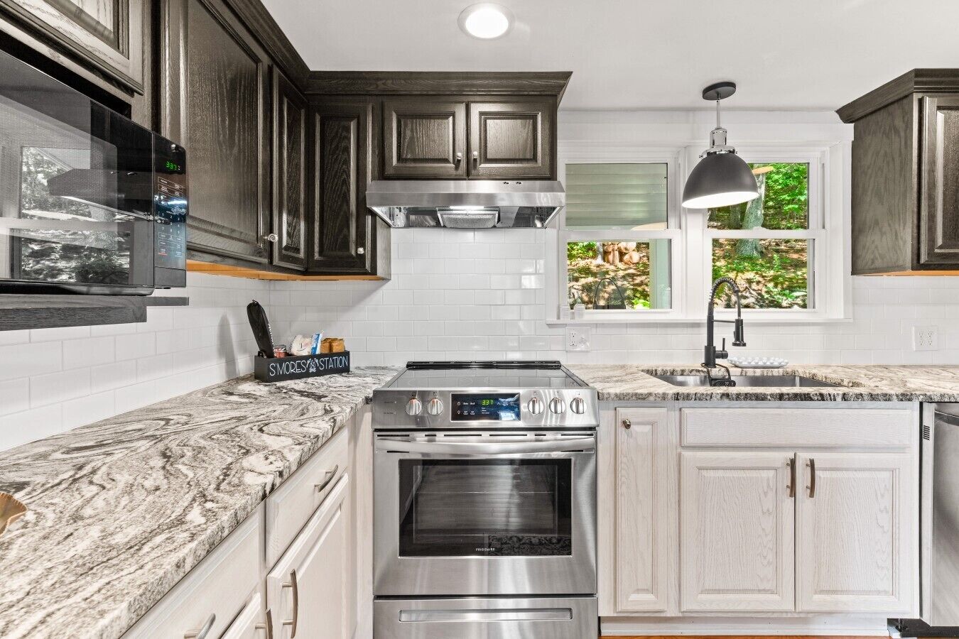 A kitchen with dark wood cabinets, white subway tiles, a stainless steel range, and a window with a view of greenery.