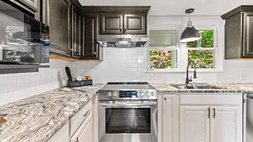 A kitchen with dark wood cabinets, white subway tiles, a stainless steel range, and a window with a view of greenery.