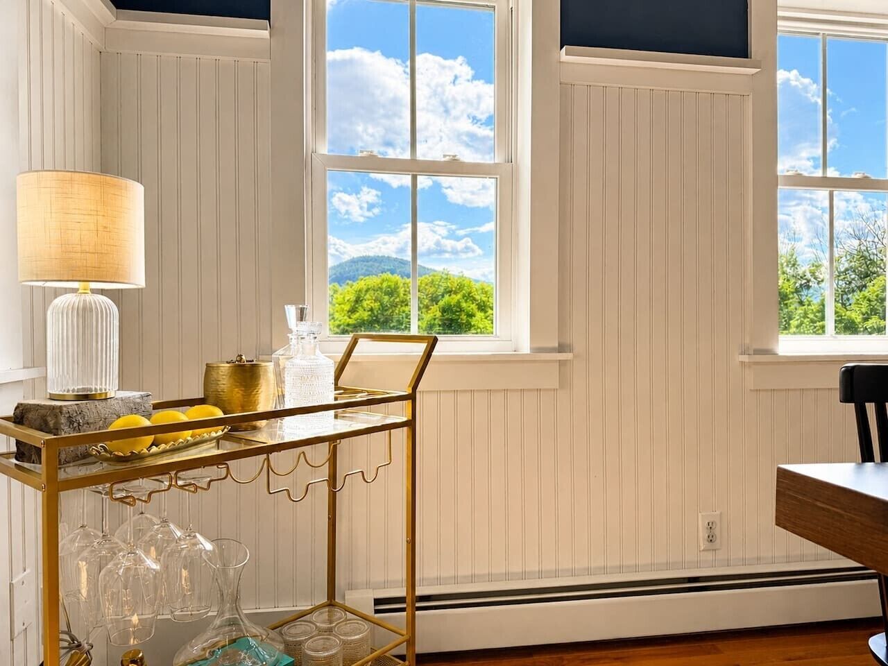 Une pièce avec une table et une chaise, une fenêtre donnant sur un espace verdoyant et un radiateur.