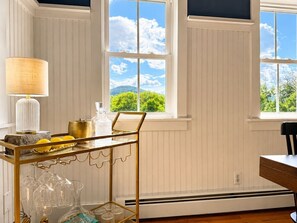 Une pièce avec une table et une chaise, une fenêtre donnant sur un espace verdoyant et un radiateur.