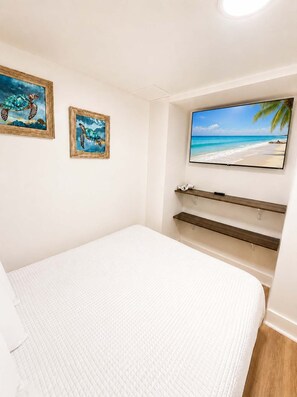 Ein Schlafzimmer mit einem Bett, einem Fernseher und zwei gerahmten Bildern von Meeresschildkröten.