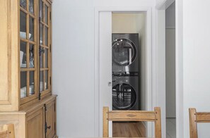 Eine kompakte Küche mit integrierter Waschmaschine und Trockner, Holzschränken und einem Essbereich mit Holztisch und Stühlen.