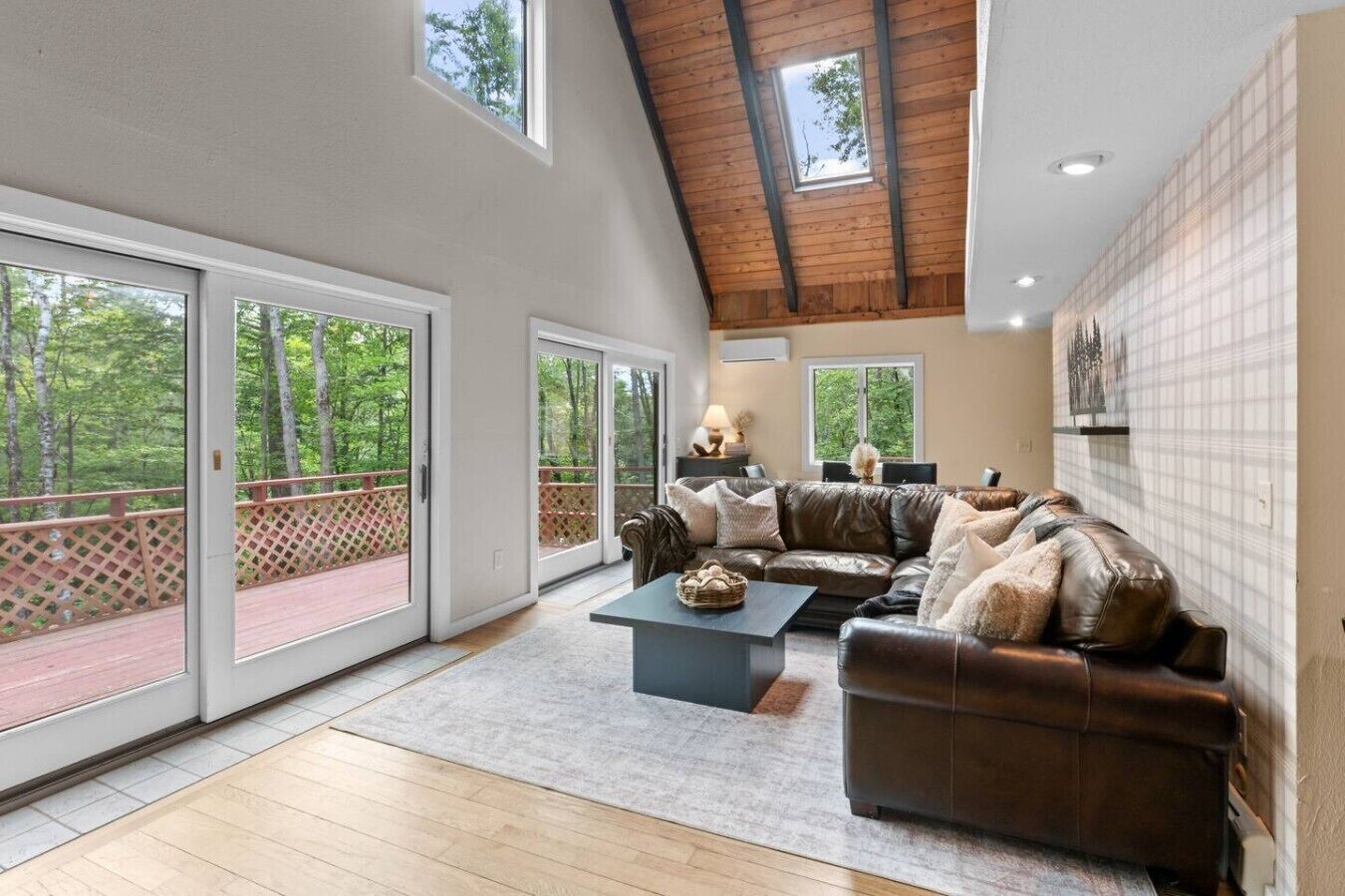 A spacious living room with a high ceiling, large sliding glass doors, a leather sofa, and a coffee table.