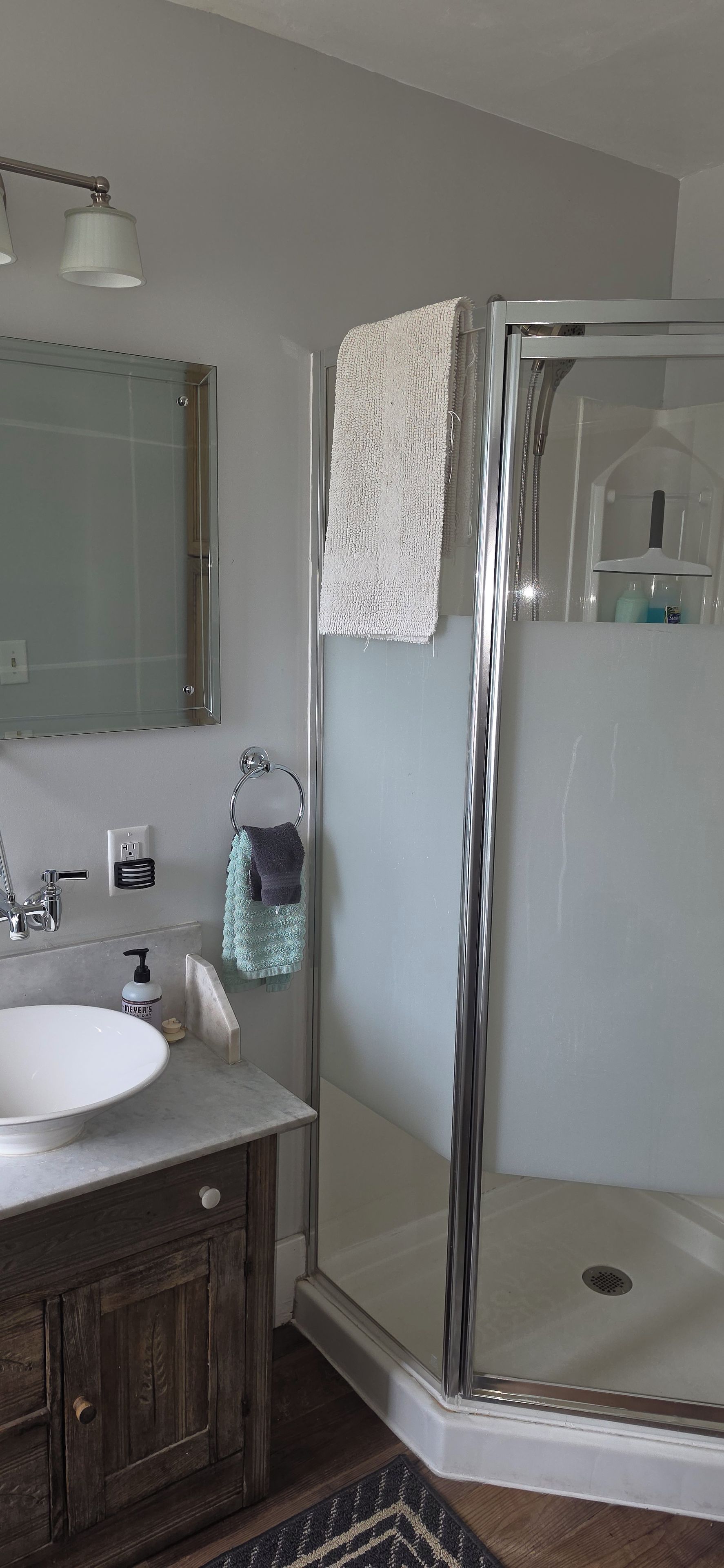 A bathroom with a glass-enclosed shower, a sink, and a mirror.