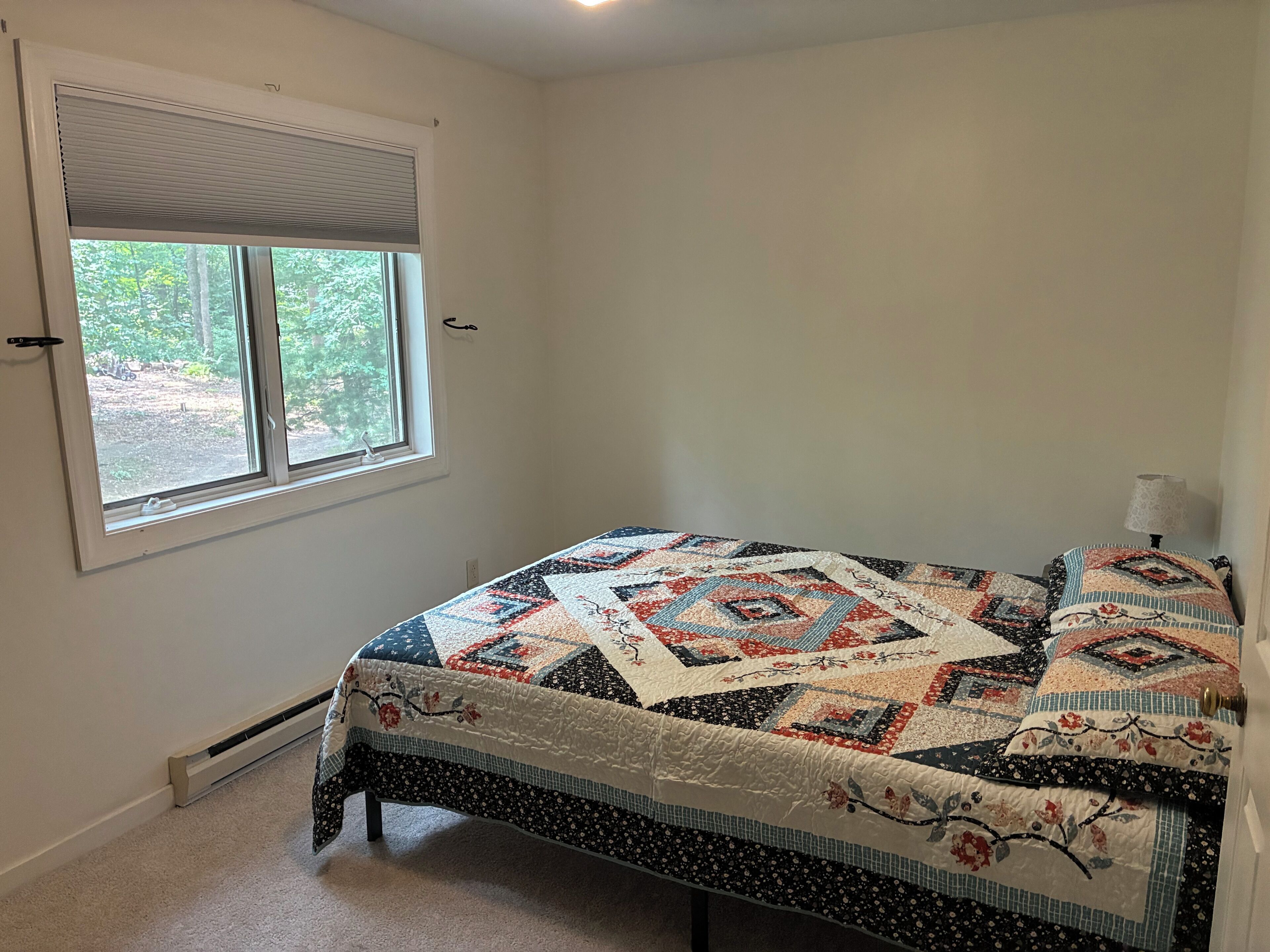 Un dormitorio con cama, ventana con persianas y radiador.