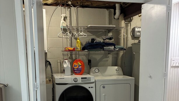 Un cuarto de lavandería con lavadora, secadora y estantes con productos de limpieza.