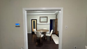 A dining area with a round table and four chairs, a framed mirror on the wall, and a door leading to another room. - Spacious Brooklyn 4BR/2BA Across 2 Private Floors with Yard (Brooklyn)