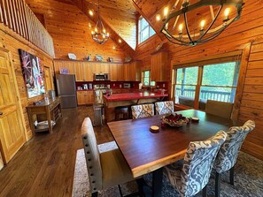 Ein Holzblock-Interieur mit Essbereich, Küche und großen Fenstern.