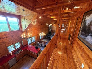 Un interior de cabaña espacioso con comedor, cocina y ventanas amplias que ofrecen vistas.