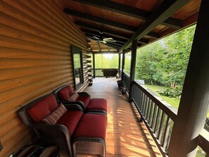 Eine überdachte Veranda mit Korbmöbeln und Blick auf die grüne Umgebung.