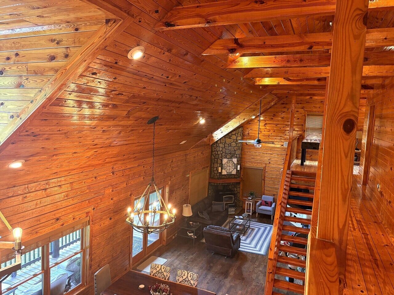 Ein Holzinnenraum mit Kamin, Sitzgruppe und einer Treppe.