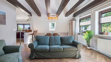 Una sala de estar moderna con un sofá, una mesa de comedor y una cocina al fondo.