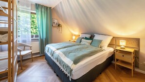 A bedroom with a bed, bedside tables, a chair, a wardrobe, and a window with curtains. - Apartment "Kleiner Anker" with Private Terrace, Garden, and Wi-Fi (Papendorf)