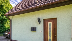 A building with a tiled roof, a wooden door, and a mailbox on the wall. - Apartment "Kleiner Anker" with Private Terrace, Garden, and Wi-Fi (Papendorf)