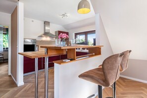 A modern kitchen with a wooden bar counter, a built-in oven, and a pendant light. - Apartment "Kleiner Anker" with Private Terrace, Garden, and Wi-Fi (Papendorf)