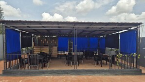 An outdoor covered patio with tables and chairs, a staircase, and a blue curtain backdrop. - 2-bedroom serviced apartment in serene Benin City with AC comfort (Benin City)