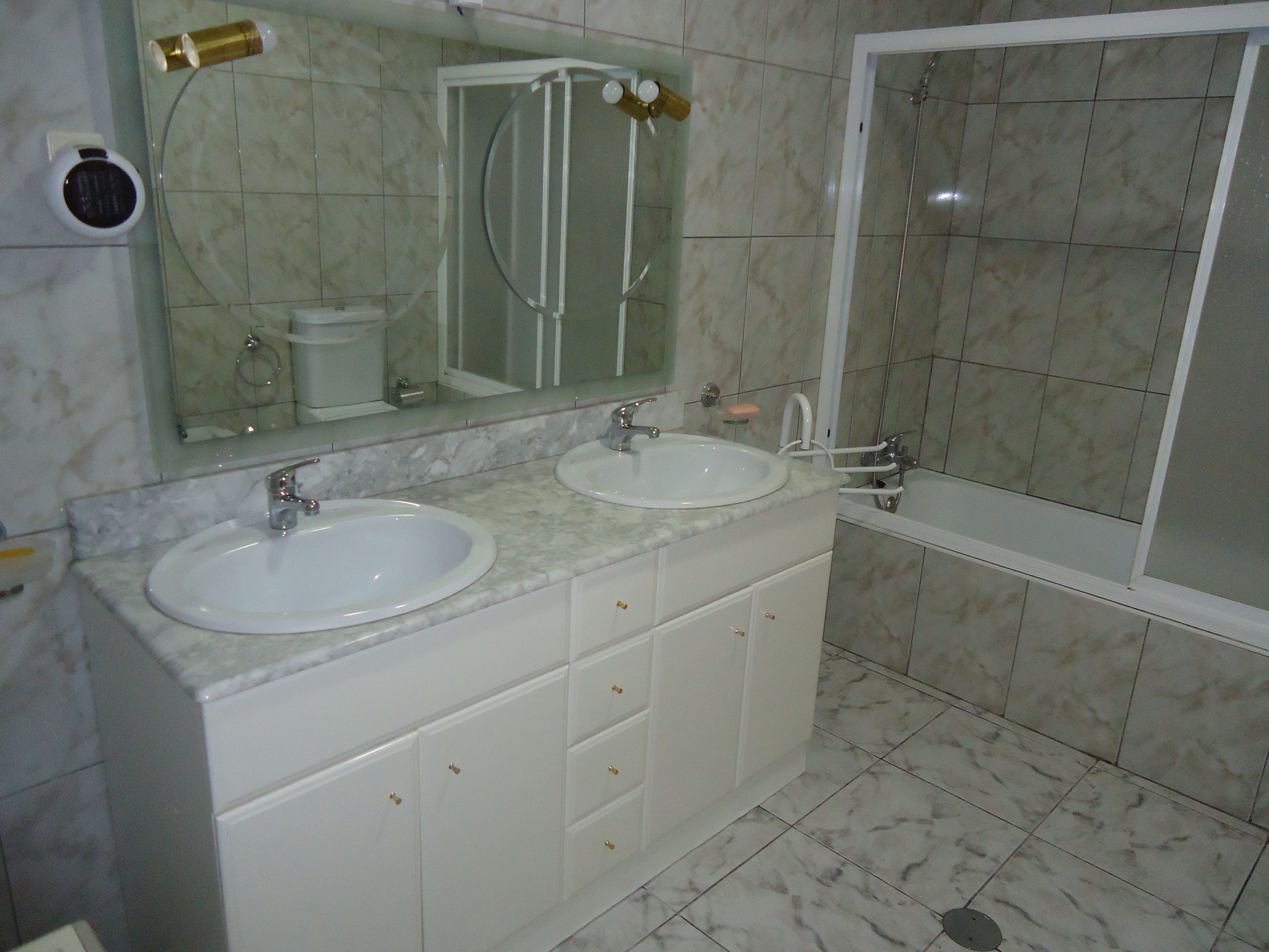 A bathroom with two sinks, a mirror, a shower, and a toilet.