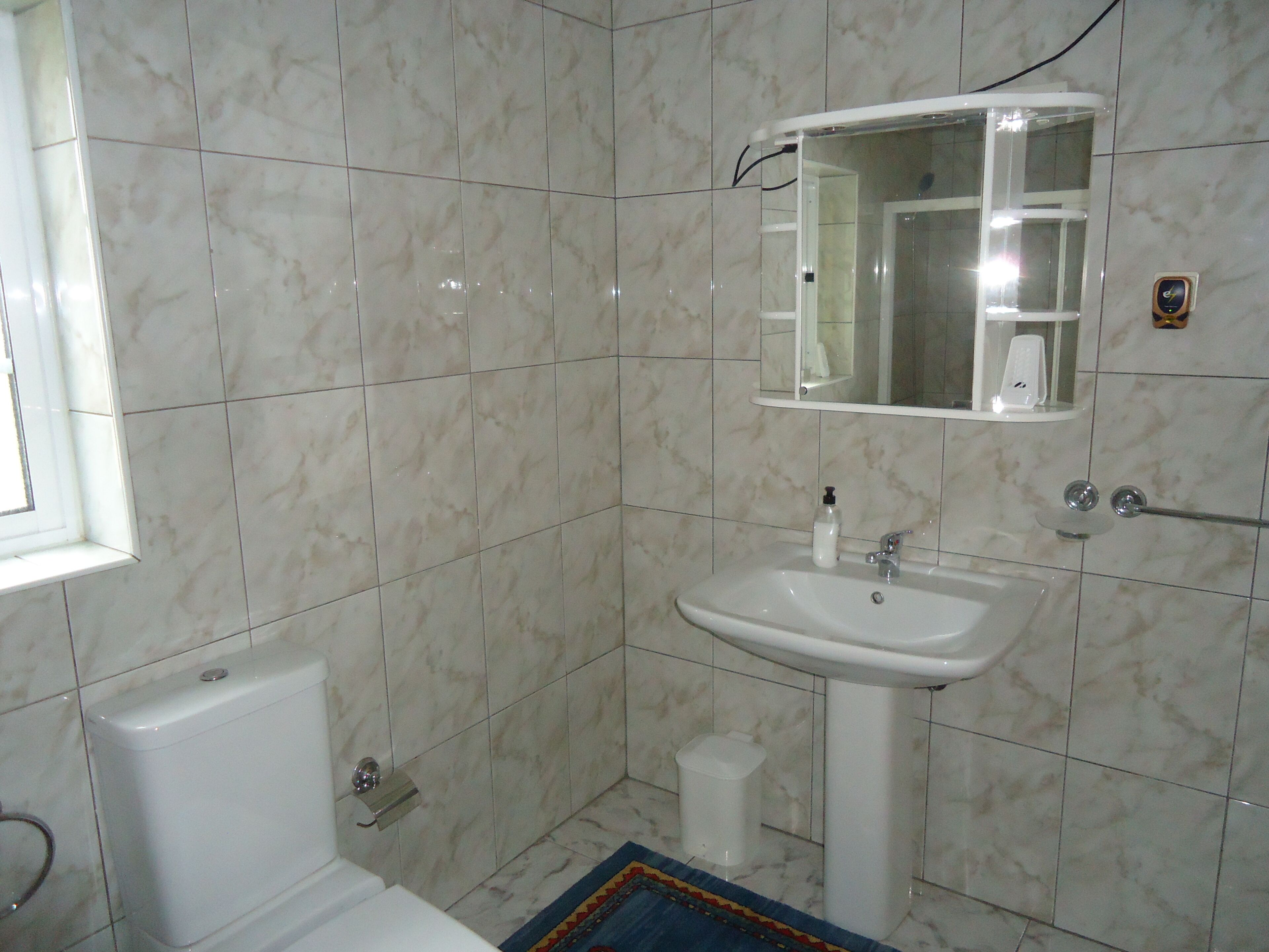 Un baño con lavamanos, espejo y retrete blancos.
