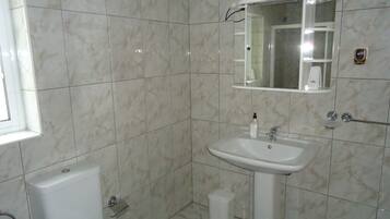 Un baño con lavamanos, espejo y retrete blancos.