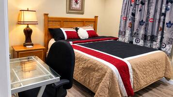 A hotel room with a wooden bed, a desk with a lamp, and a glass partition.