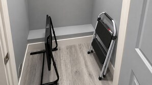 Ein kleiner begehbarer Kleiderschrank mit grauer Wand, weißer Tür und grauem Boden.
