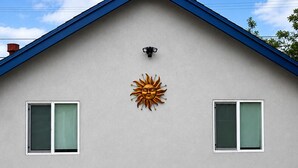 Ein Haus mit Satteldach, zwei Fenstern und einer Sonnendekoration an der Fassade.