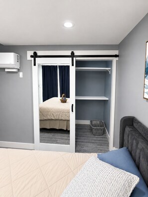 A bedroom with a bed, a wardrobe, a grey sofa, and a laundry basket. - Brand-New, Lovely 2026 ADU - Near Major Hospitals, SoFi Stadium & LAX (Los Angeles)