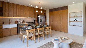 Uma cozinha moderna com armários de madeira, uma ilha central e uma área de jantar com mesa redonda e cadeiras.