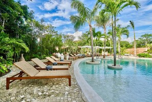A poolside area with lounge chairs and palm trees. - Luxury 3BR Condo at Aflora in Aldea Zama (Tulum)