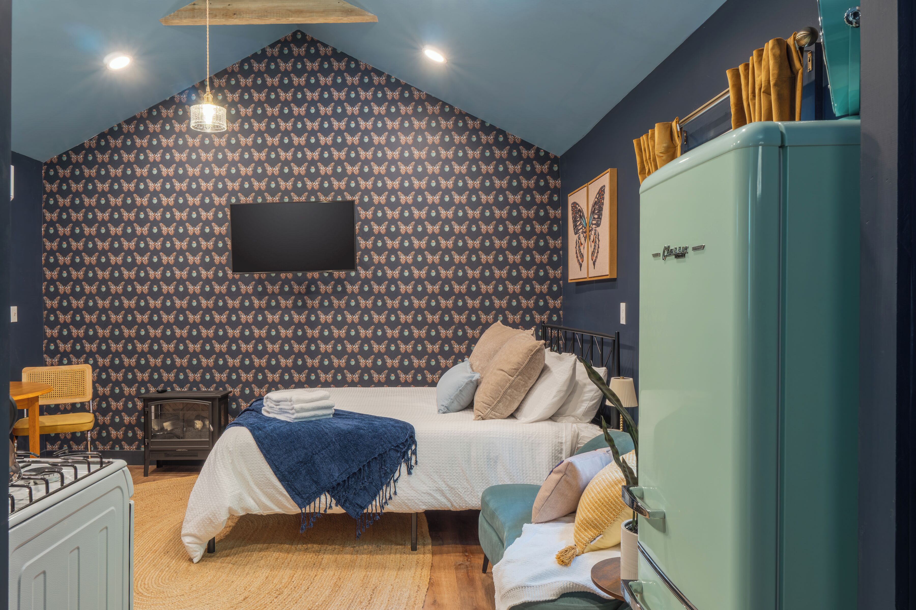 A bedroom with a bed, a dresser, a vintage-style radio, and a wall-mounted TV.