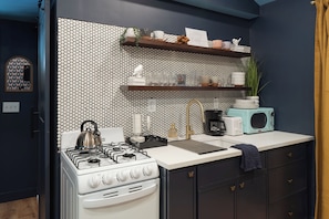 A kitchen with a white stove, a coffee maker, and a microwave on the counter.
