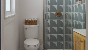 Une salle de bain équipée de toilettes, d’une douche à parois de verre et d’un meuble en bois.