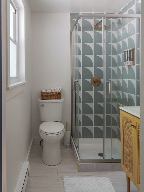 Ein Badezimmer mit Toilette, einer Glasdusche und einem Holzschrank.
