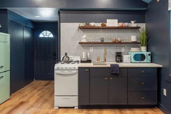 Una cocina con estufa, armarios y microondas.