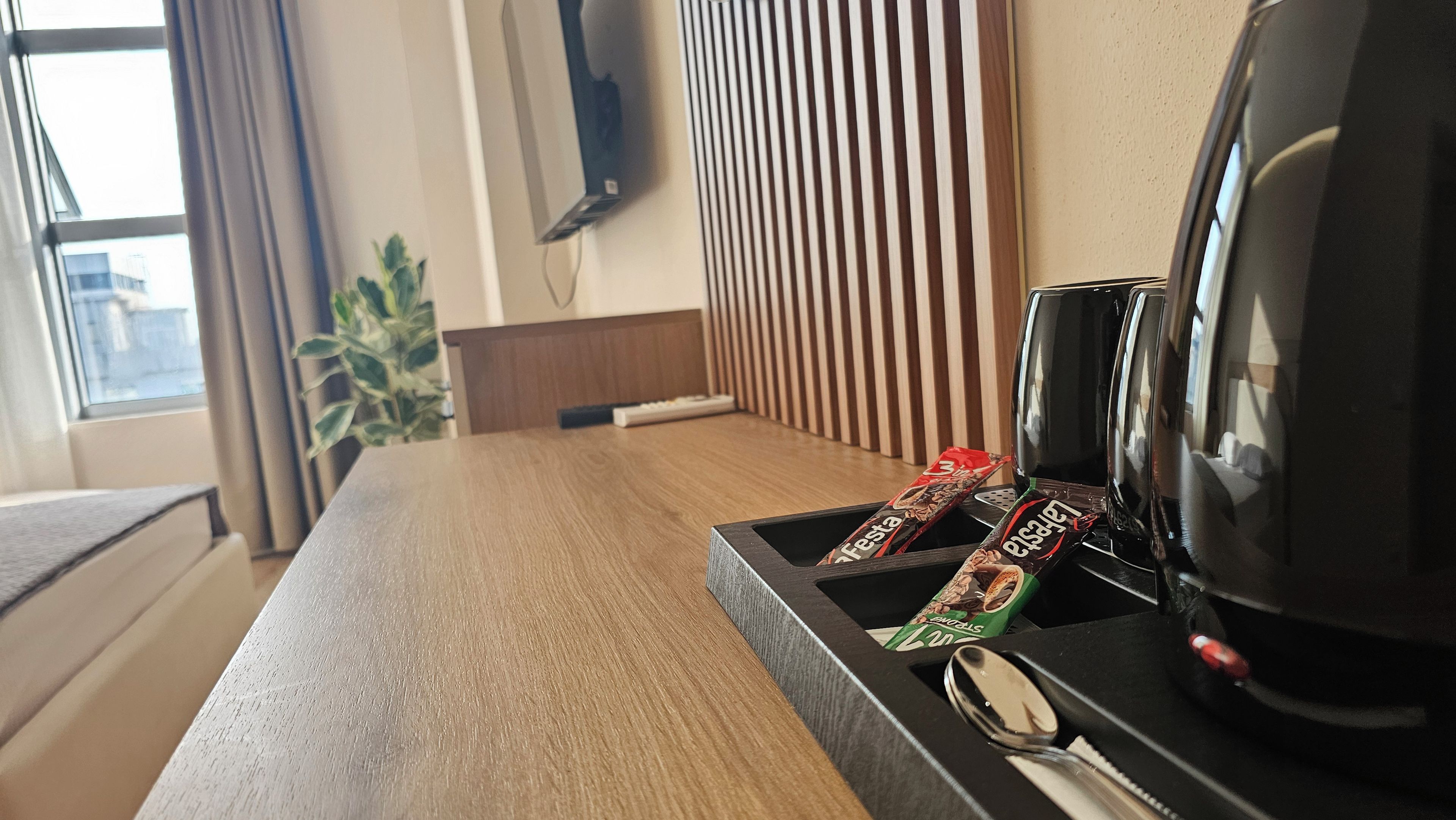 A hotel room with a wooden table, a black coffee maker, and two chocolate bars.
